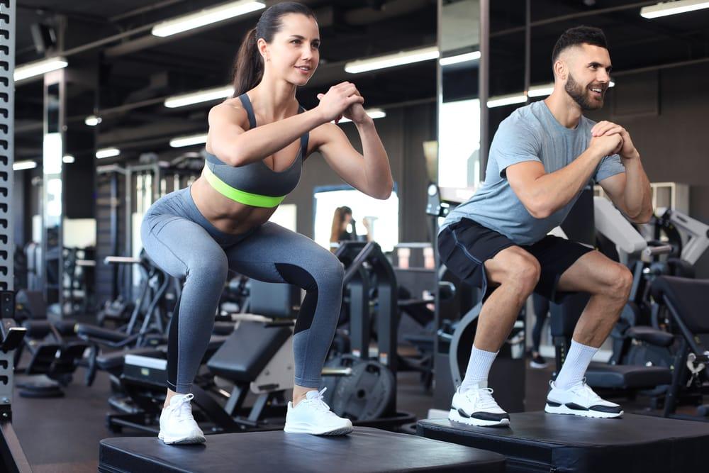 Man and woman performing squats in the gym